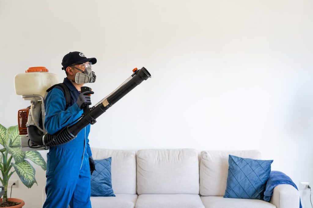 Hombre con uniforme azul sosteniendo una aspiradora, realizando fumigación para casas en Guatemala.
